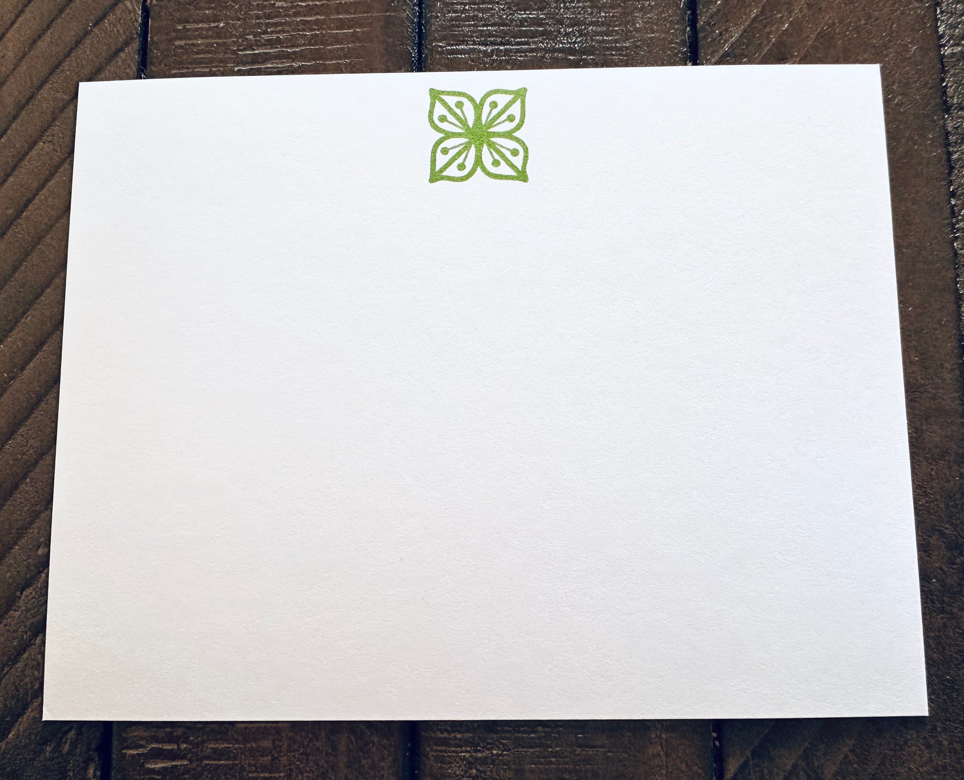 White paper with a green floral design on a wooden surface